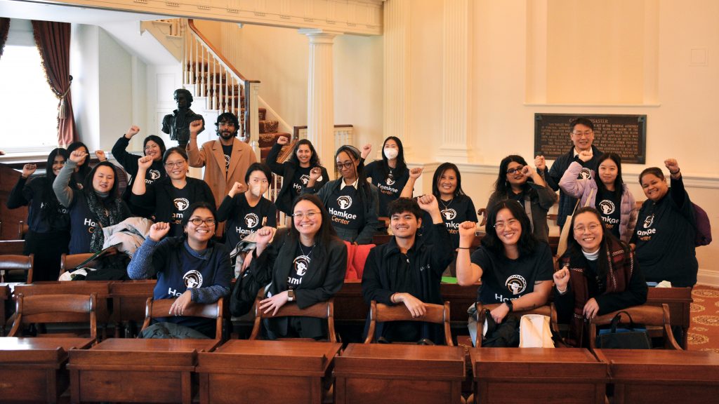Group photo of Hamkae Center staff and community members holding up a solidarity fist in a room with antique desks at the Virginia General Assembly as part of Hamkae Center's 2025 Advocacy Day.