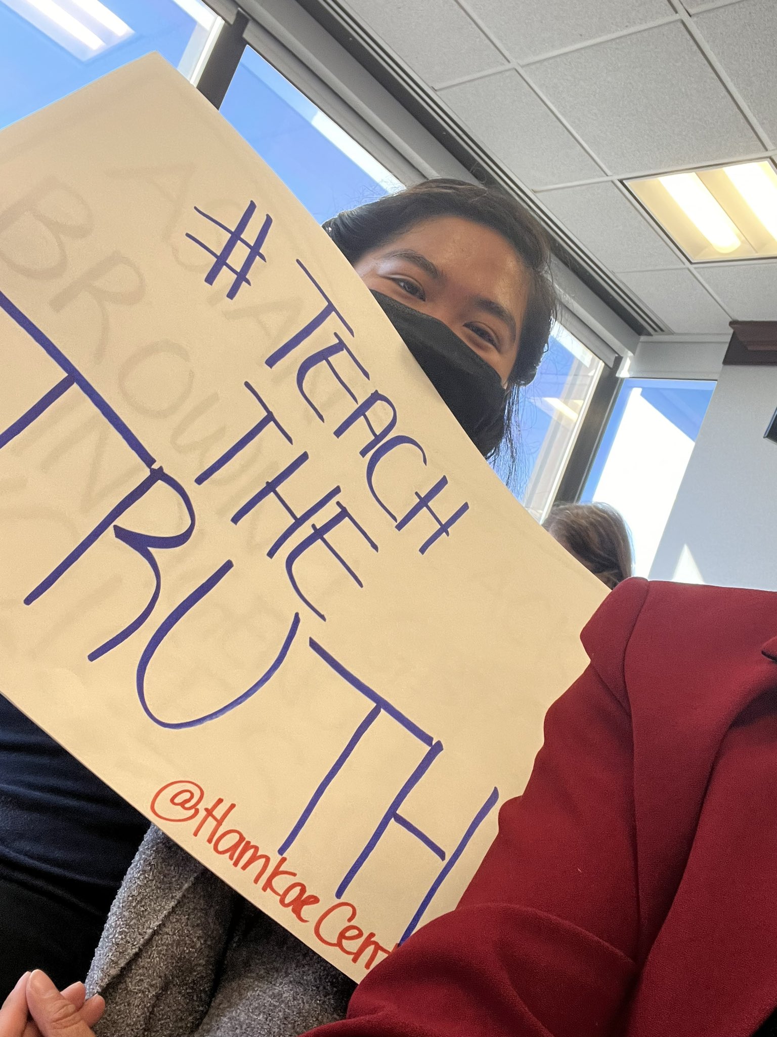 Ha Tang holds up a sign that says "#TeachTheTruth" in the audience of the Virginia Board of Education meeting in Richmond, VA on November 17, 2022.