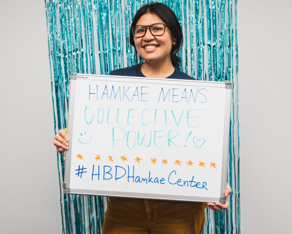 Zowee holds up a sign that says, "Hamkae means collective power! ♥️"