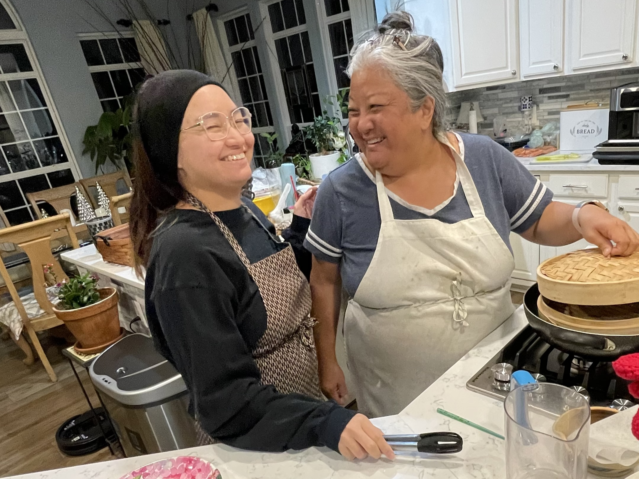 Photo of Ashley Elstad and their mom smiling and laughing with each other in their kitchen.