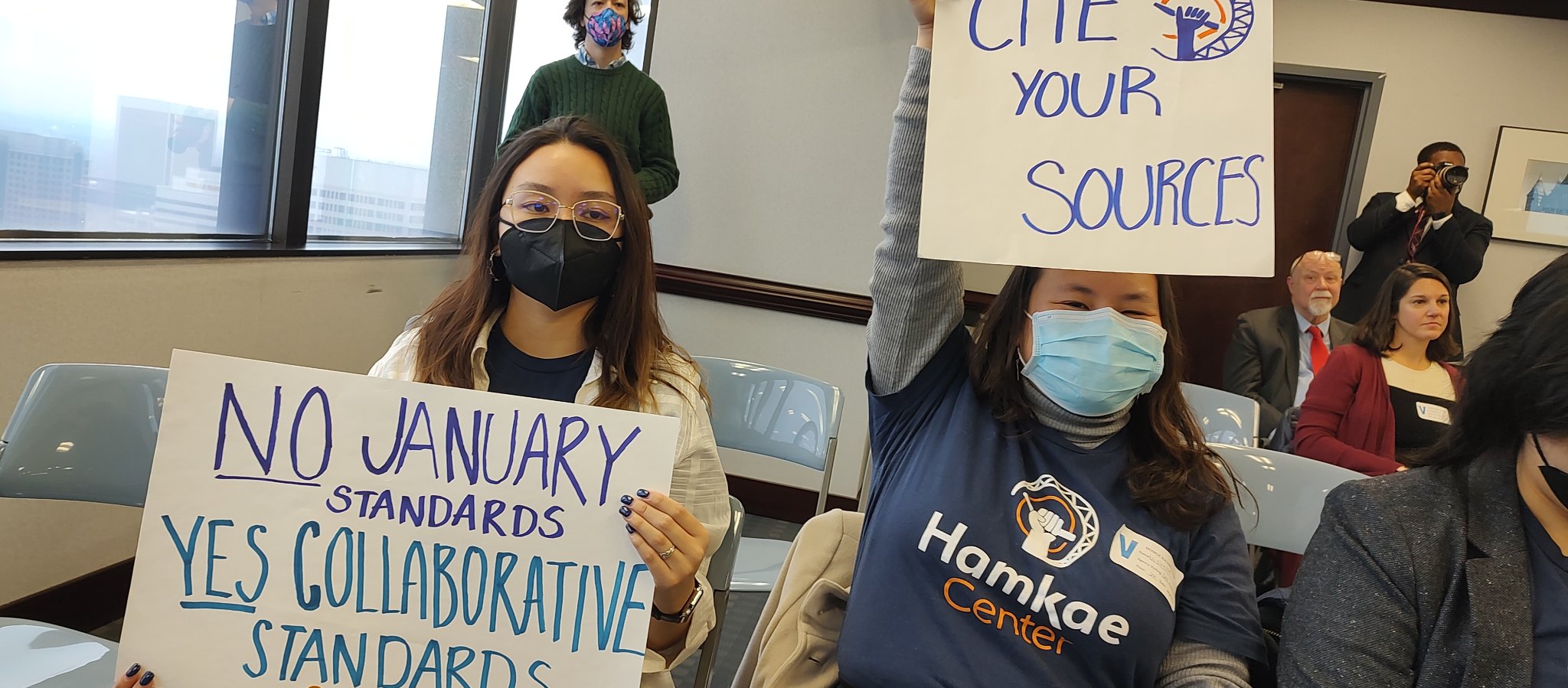 Asian American Virginians hold up handmade signs that say, "NO January Standards, YES Collaborative Standards" and "Cite Your Sources" at the Virginia Board of Education meeting in Richmond, VA on Feb. 2, 2023.